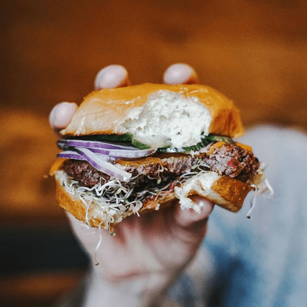 A hand holding a big burger