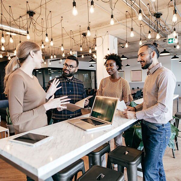 A group of people talking around a table and laptop