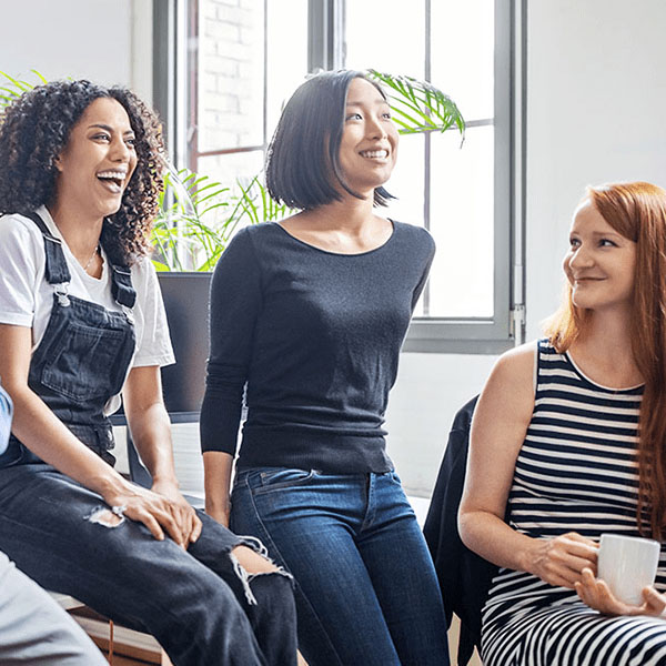 Three women sitting causally and laughing